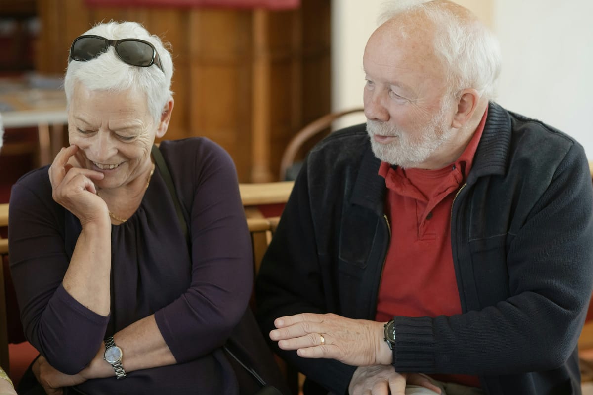 Older couple talking and smiling in a welcoming room