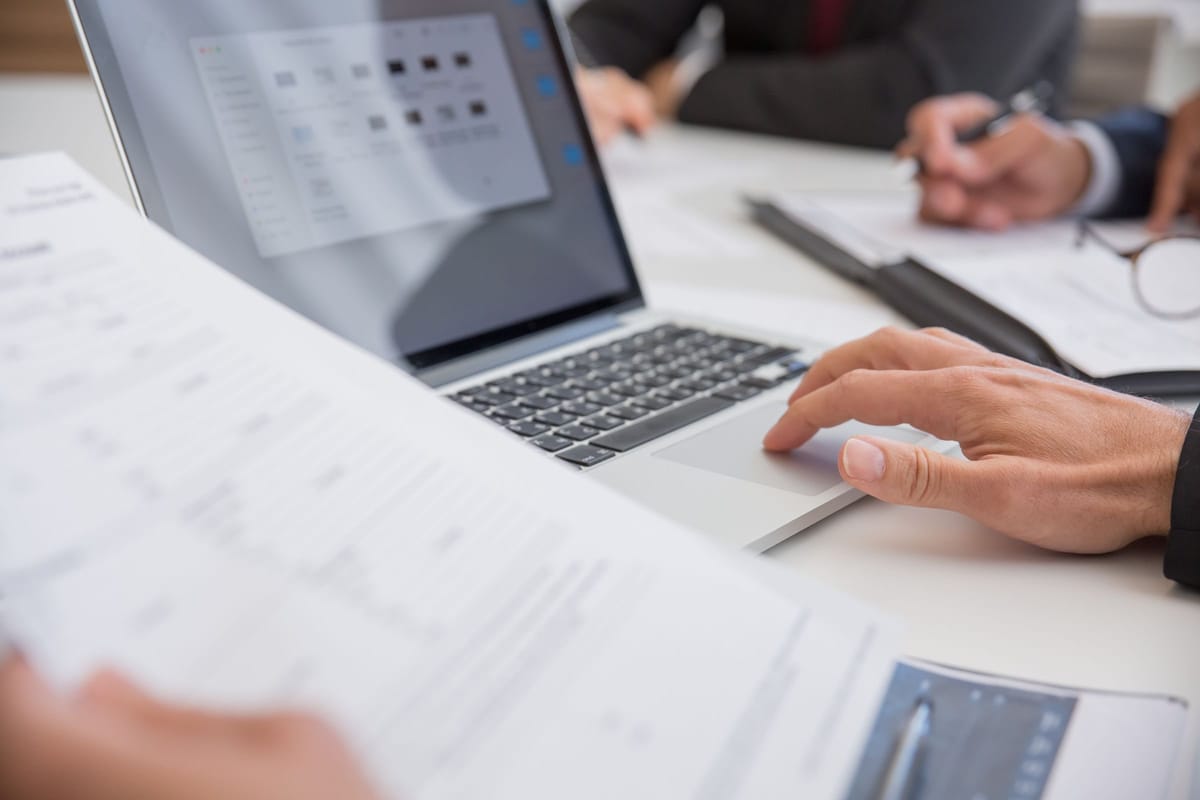 Colleagues review documents and a laptop in a professional office