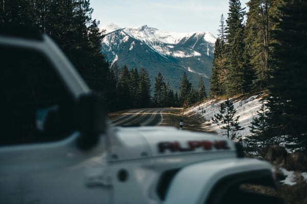 Vehicle travelling toward snowy mountains on a road
