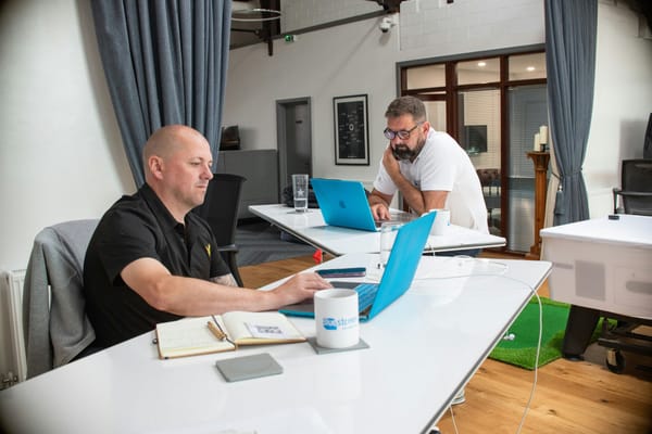 Two people collaborating with laptops in a modern office, no visible brand
